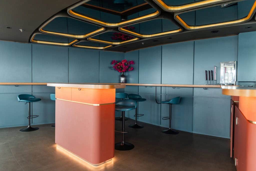 Stylish bar area inside the Berlin TV Tower with teal panelled walls, a honeycomb-patterned gold ceiling, and a pink curved counter.